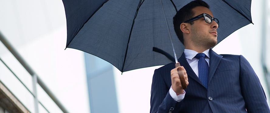 Man in a suit and sunglasses holding an umbrella