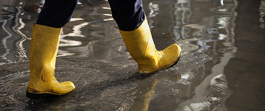 Someone wearing rain boots walking through puddles