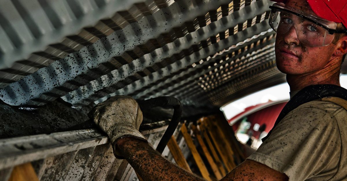 Young man wearing safety goggles and other protective clothing while in the workplace.