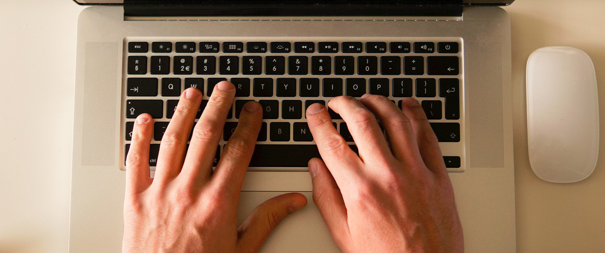 Hands typing on a laptop