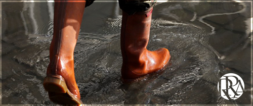 Someone walking through a puddle of water wearing boots