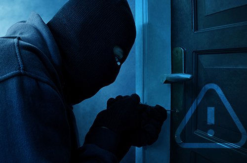 Burglar with full head mask picking at a door lock