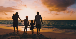 Family of four walking beach with sunset