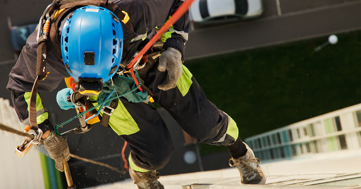 Industrial worker hangs over residential building while washing exterior façade glazing