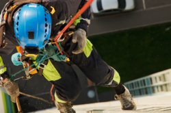 Industrial worker hangs over residential building while washing exterior façade glazing